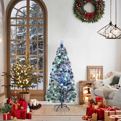 A 5 ft pre-lit fiber optic Christmas tree in green and white, twinkling with colorful lights, displayed in a cozy holiday living room.
