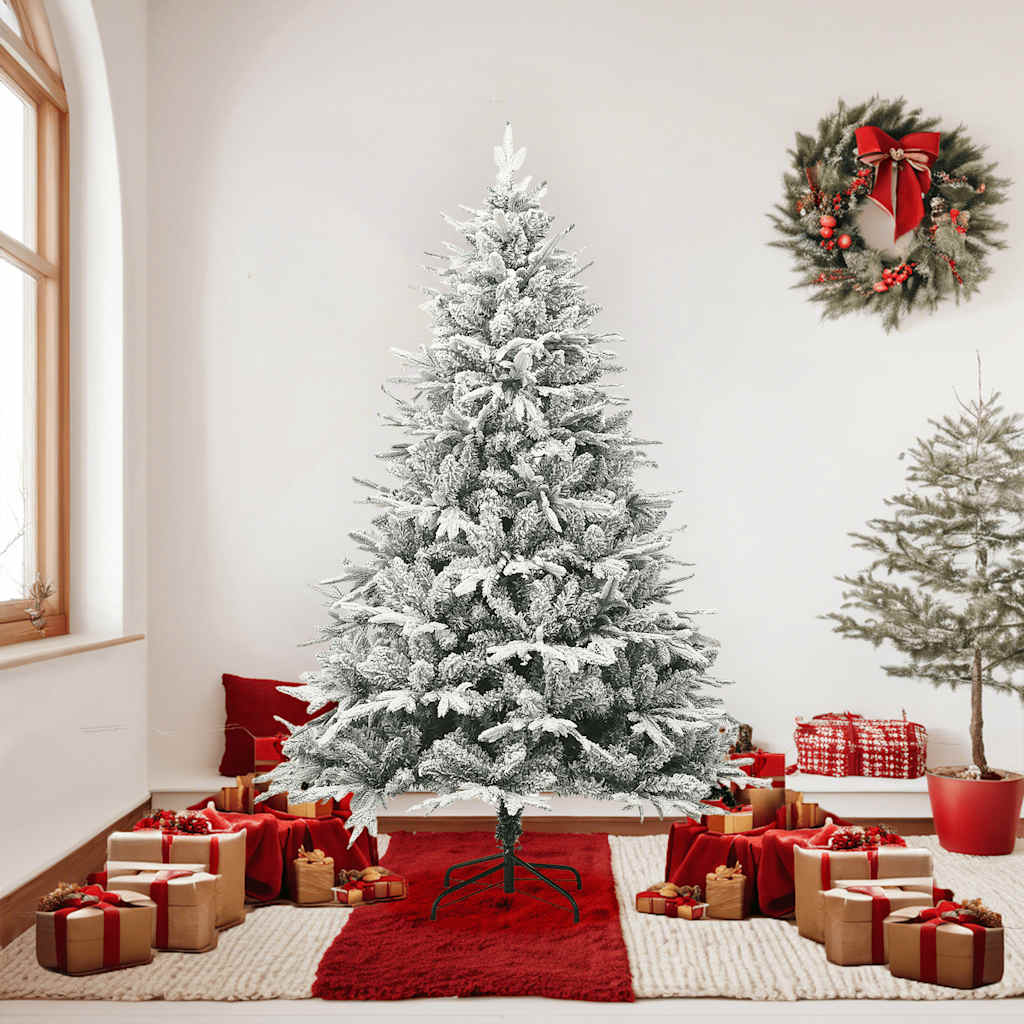 A 6ft flocked snow green artificial Christmas tree with PVC and PE branches, standing in a festive room with gifts and wreaths.