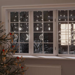 White LED fairy lights in star and moon shapes draped over a window with Christmas tree.