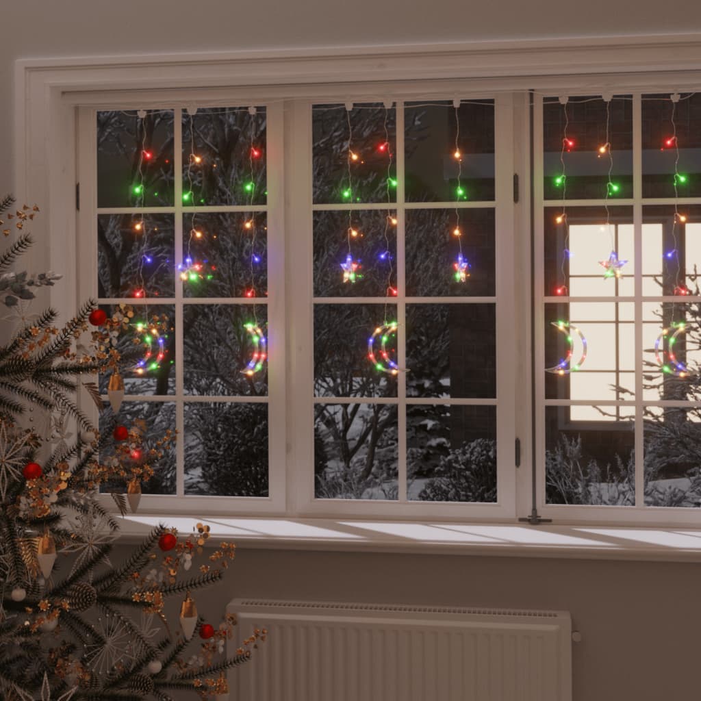 Colorful LED fairy lights with star and moon shapes on a window with Christmas tree.