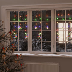 Colorful LED fairy lights with star and moon shapes on a window with Christmas tree.
