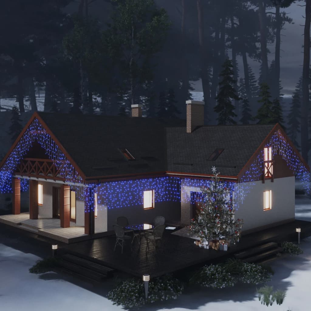 Blue LED curtain icicle lights draped on a snowy house with trees at night.