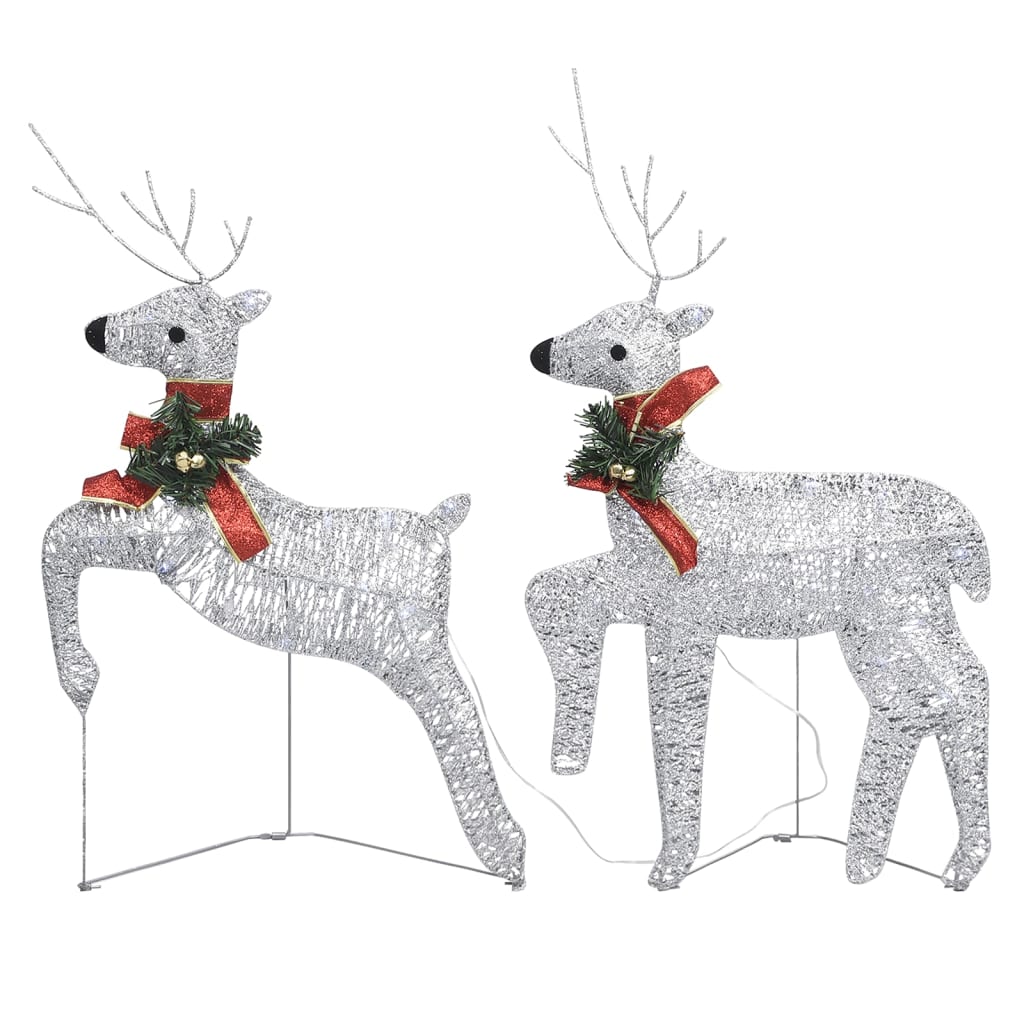 Two silver, glitter-covered reindeer Christmas decorations with red bows and green accents.