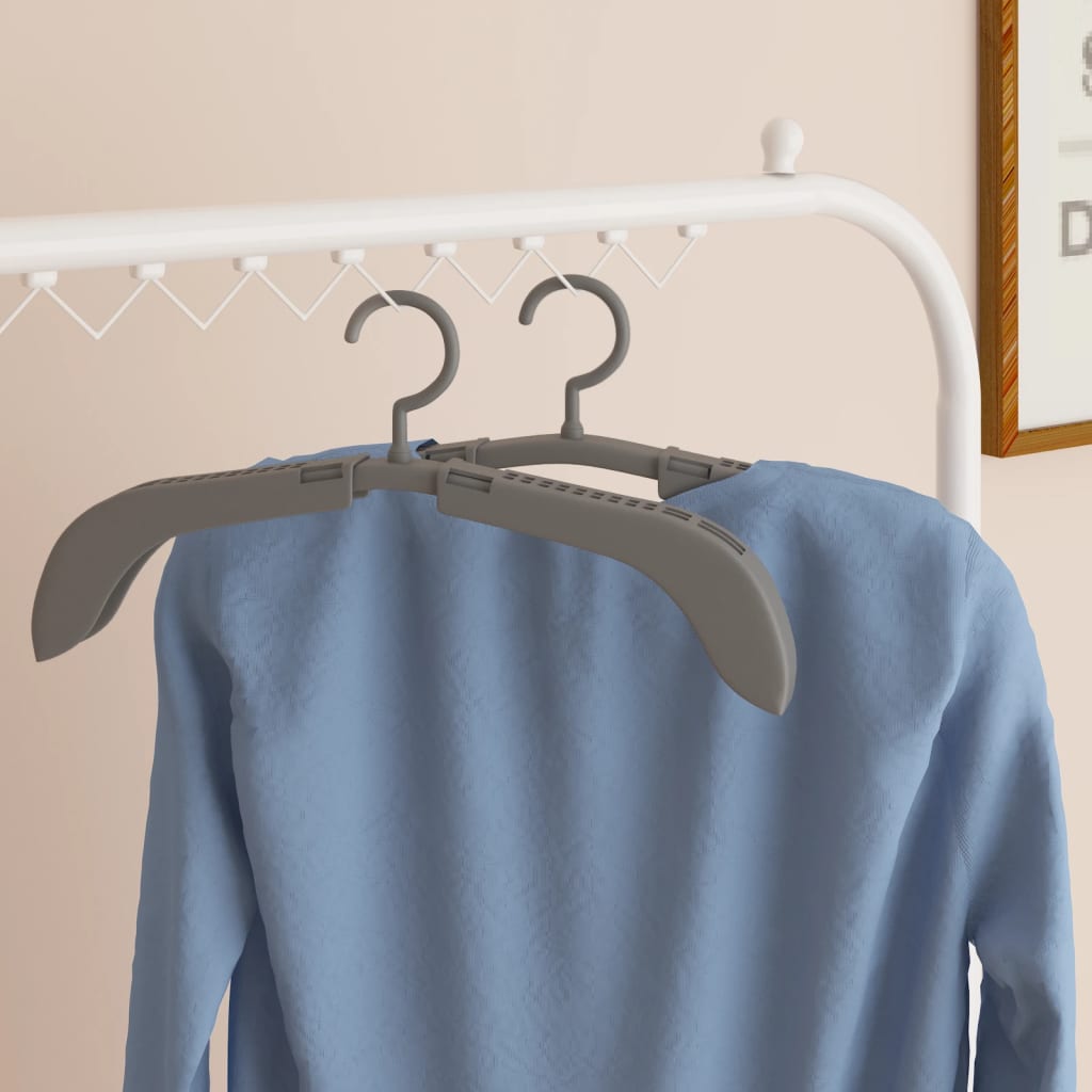 Gray extendable clothes hanger holding a blue sweater on a white rack.