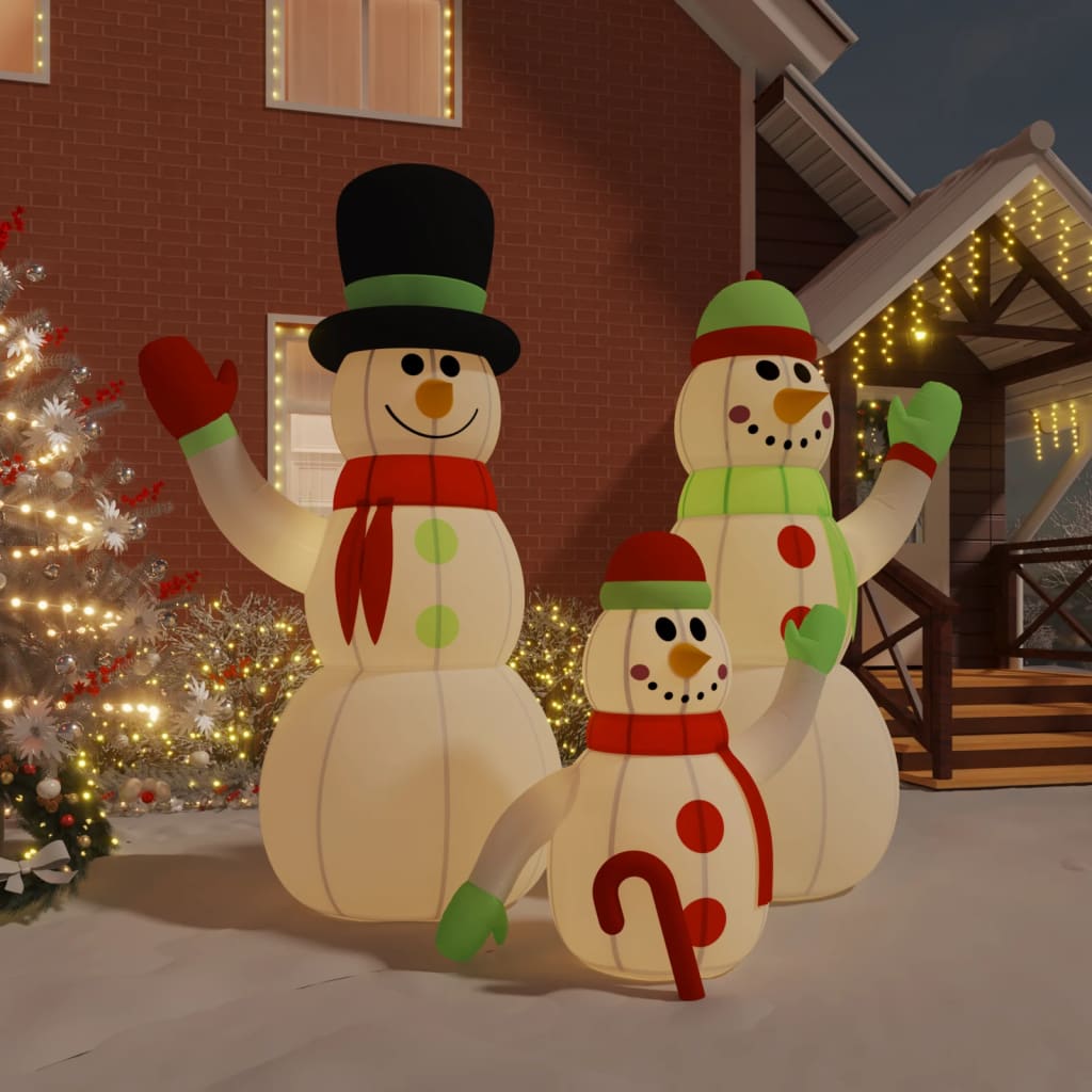 An inflatable snowman family with LED lights stands in a snowy yard.
