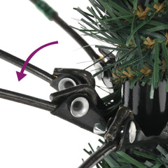 Close-up of hinged branches and black metal stand on a green artificial Christmas tree.