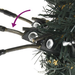 Close-up of hinged branches on a green artificial Christmas tree with PVC needles and cones.