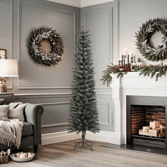 A 6 ft slim artificial Christmas tree with green PVC branches dusted in snow, standing on a steel base in a cozy gray living room.