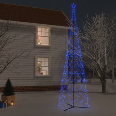 A tall blue LED Christmas cone tree with 3000 lights stands in a snowy yard beside a house.