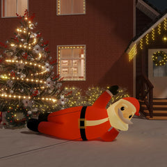 63-inch inflatable lying Santa with multicolor LED lights in front of a Christmas tree and house.