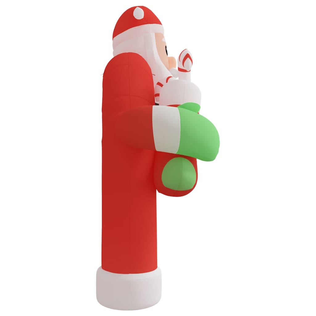 Side view of a tall red and white inflatable Santa Claus holding a candle with green gloves.