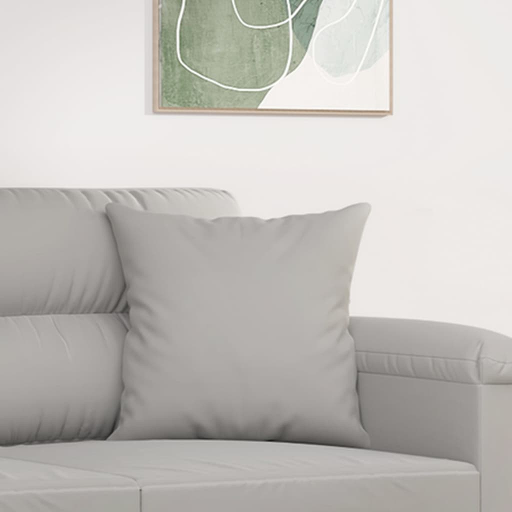 Two light gray microfiber throw pillows on a gray sofa.