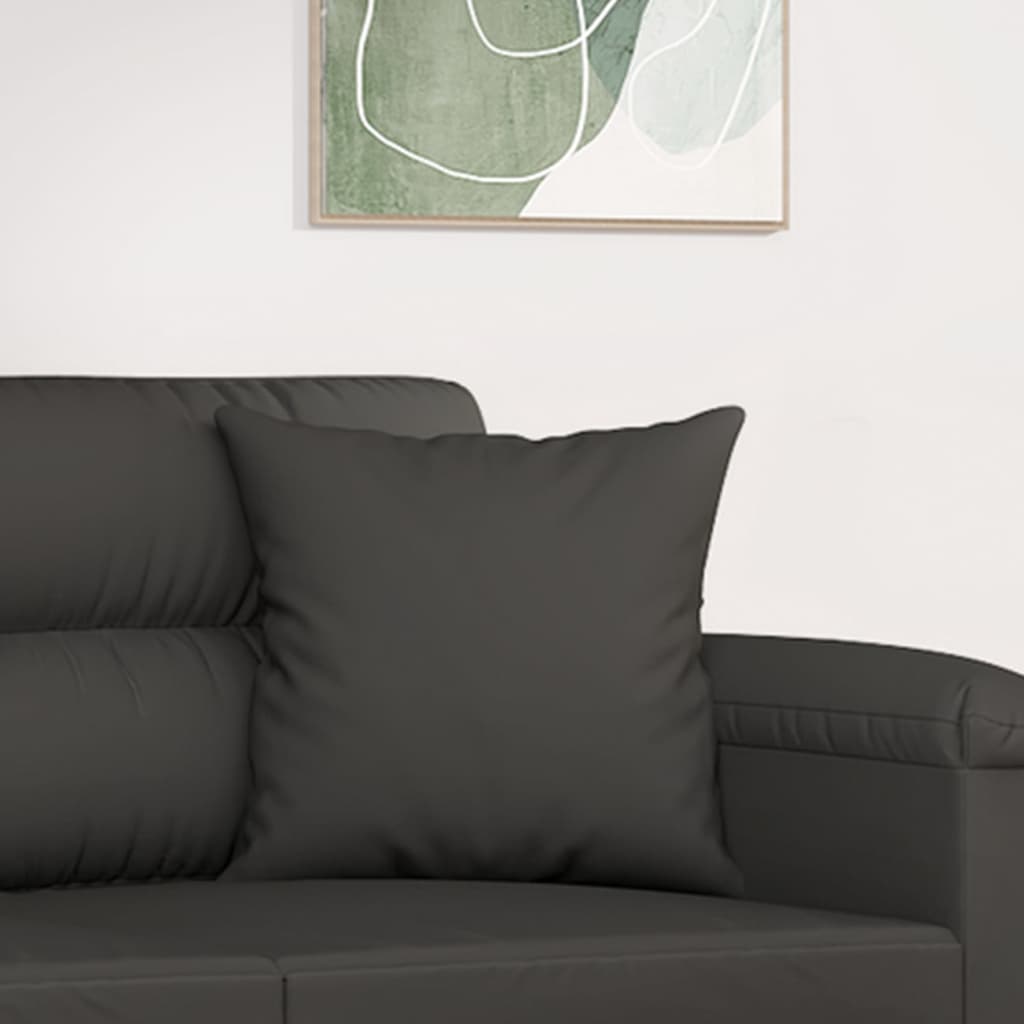 Two dark gray microfiber throw pillows on a gray couch with abstract wall art.