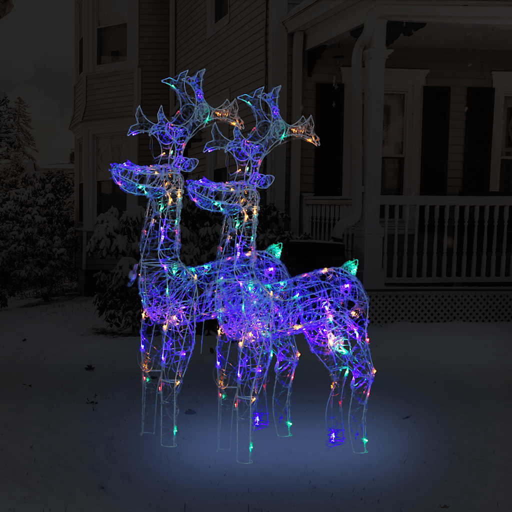 Two multicolored LED-lit acrylic reindeer decorations standing in snowy yard.