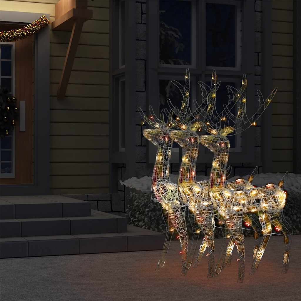 Three multicolor LED acrylic reindeer Christmas decorations glowing on a porch at night.