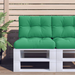 Green polyester pallet cushion with tufted design on a white pallet against a wooden fence.