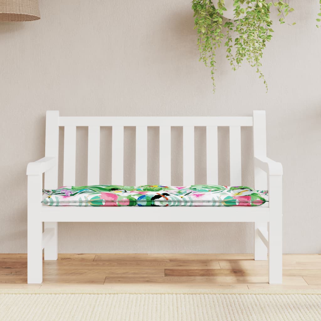 White garden bench with multicolor floral cushion featuring birds and leaves.