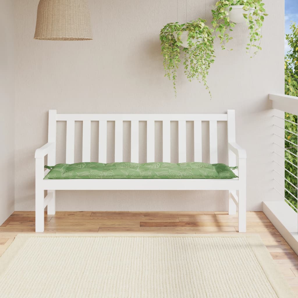 Green leaf-patterned bench cushion on white outdoor bench with cushions and plants.