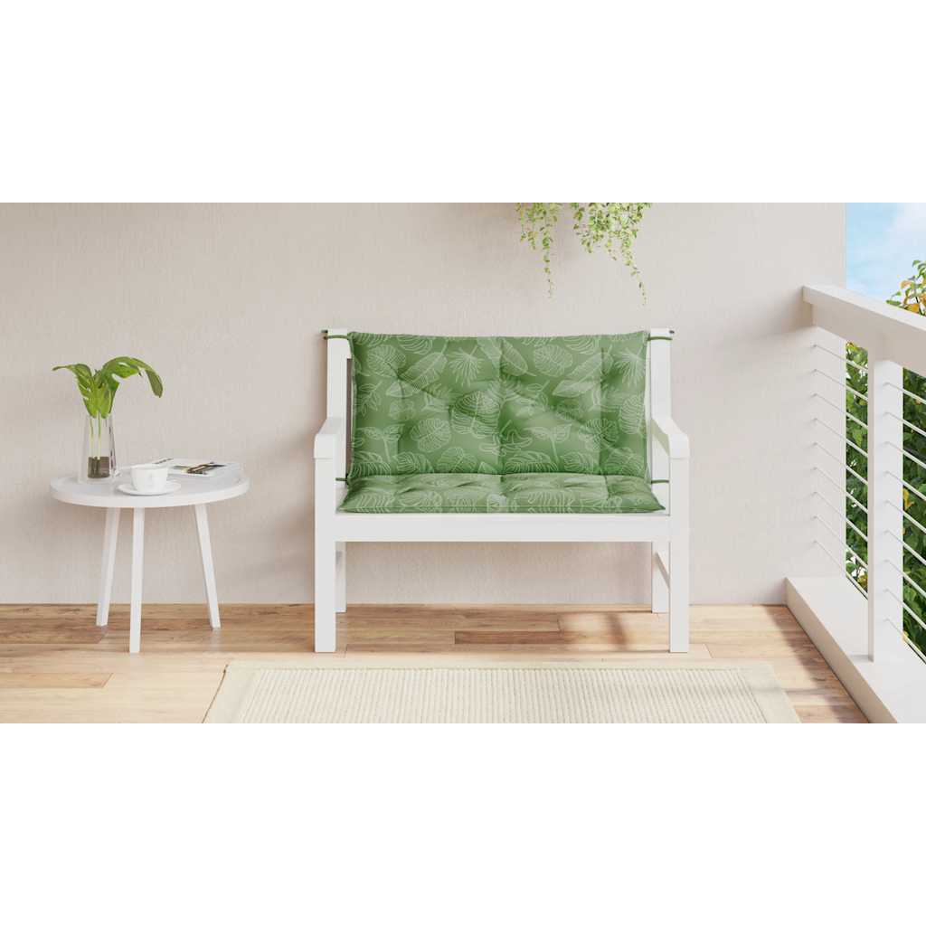 Two green leaf-patterned bench cushions with ties on a white wooden garden bench.
