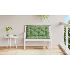 Two green leaf-patterned bench cushions with ties on a white wooden garden bench.