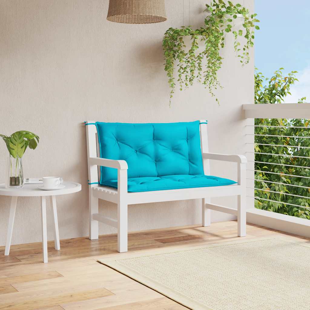 Two turquoise garden bench cushions with tufted design and non-slip ties on white bench.
