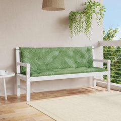Two green leaf-patterned bench cushions on a white garden bench on a balcony.