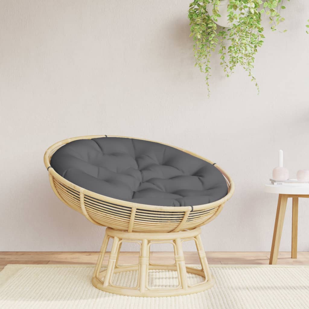 A round rattan papasan chair with a dark gray cushion sits on a light rug.