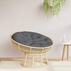 A round rattan papasan chair with a dark gray cushion sits on a light rug.
