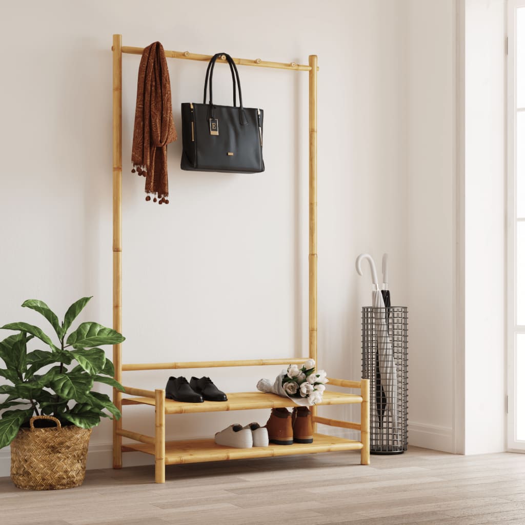 Bamboo clothes rack with upper hanging bar, lower shoe shelf, and folded clothes.
