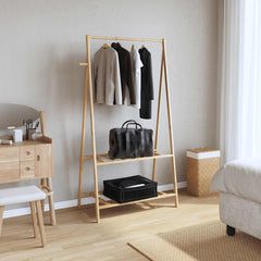 Bamboo clothes rack with shelves, holding clothes, bag, and boxes in a bedroom.