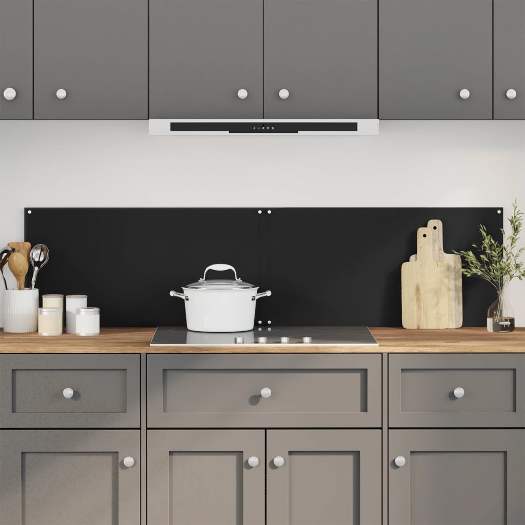 Two black tempered glass backsplash panels installed on a modern kitchen wall behind a white pot on an induction cooktop.