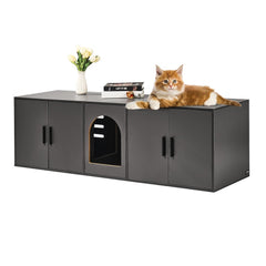 Black wooden cat litter box enclosure with arched entry, orange cat lounging on top beside books and flowers.