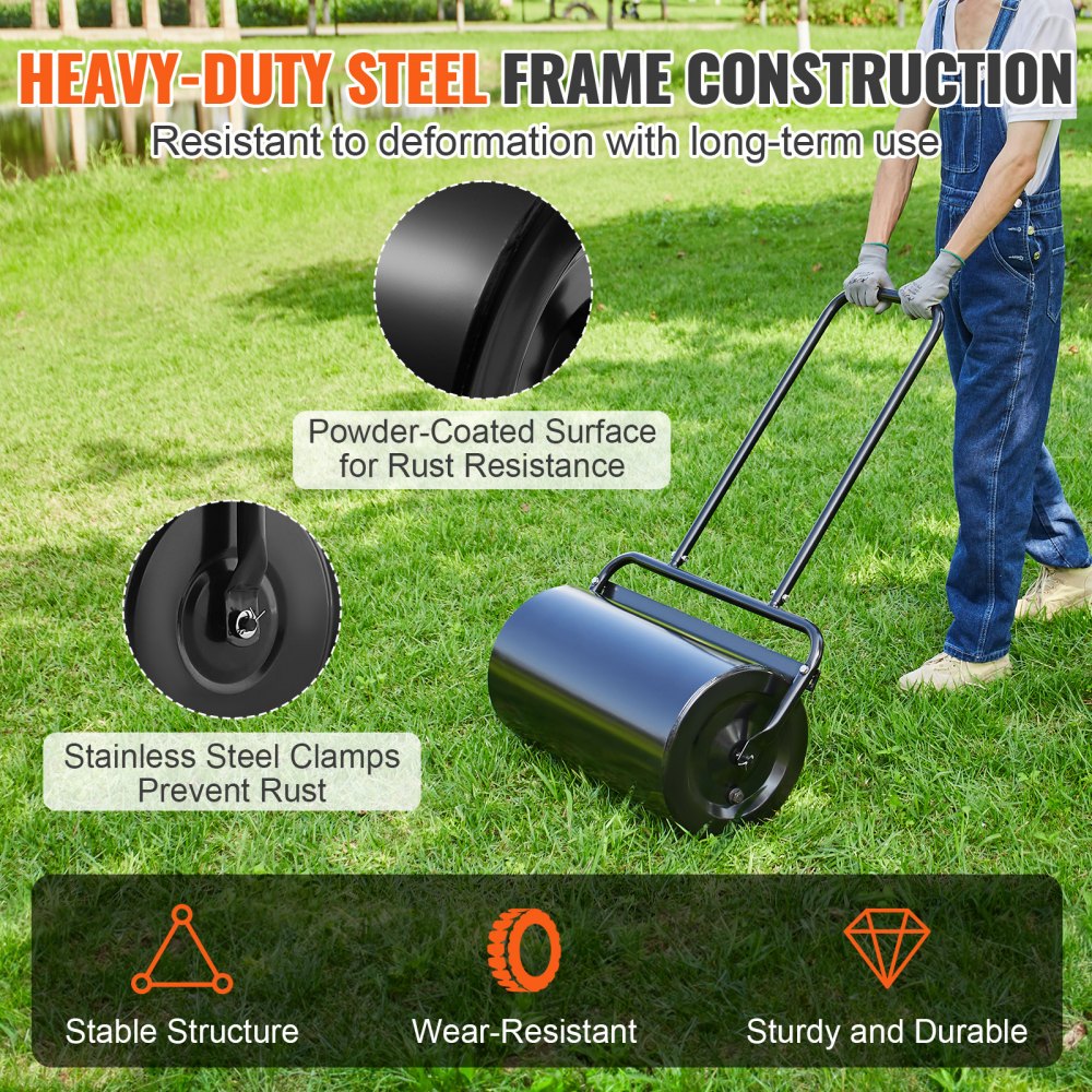 A person in overalls pushes a black steel lawn roller across a green lawn.