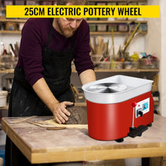 Man using red 25cm electric pottery wheel with foot pedal to shape clay on workbench.